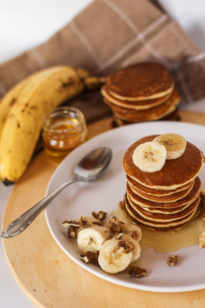 Delicious banana pancakes drizzled with honey and topped with walnuts, perfect for breakfast.