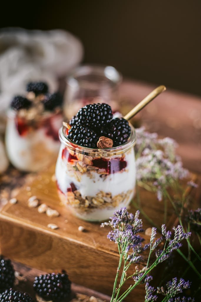 Delicious blackberry and yogurt parfait with granola served in jars and decorated with flowers.