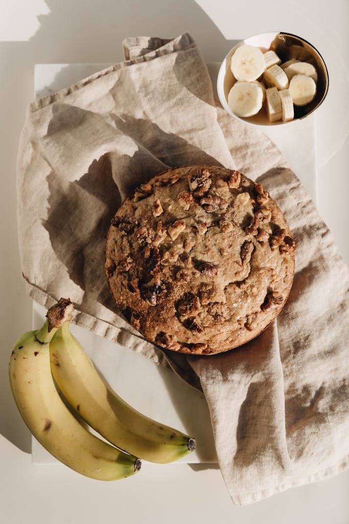 Fresh homemade banana bread accompanied by ripe bananas and slices. Perfect lighting for food photography.