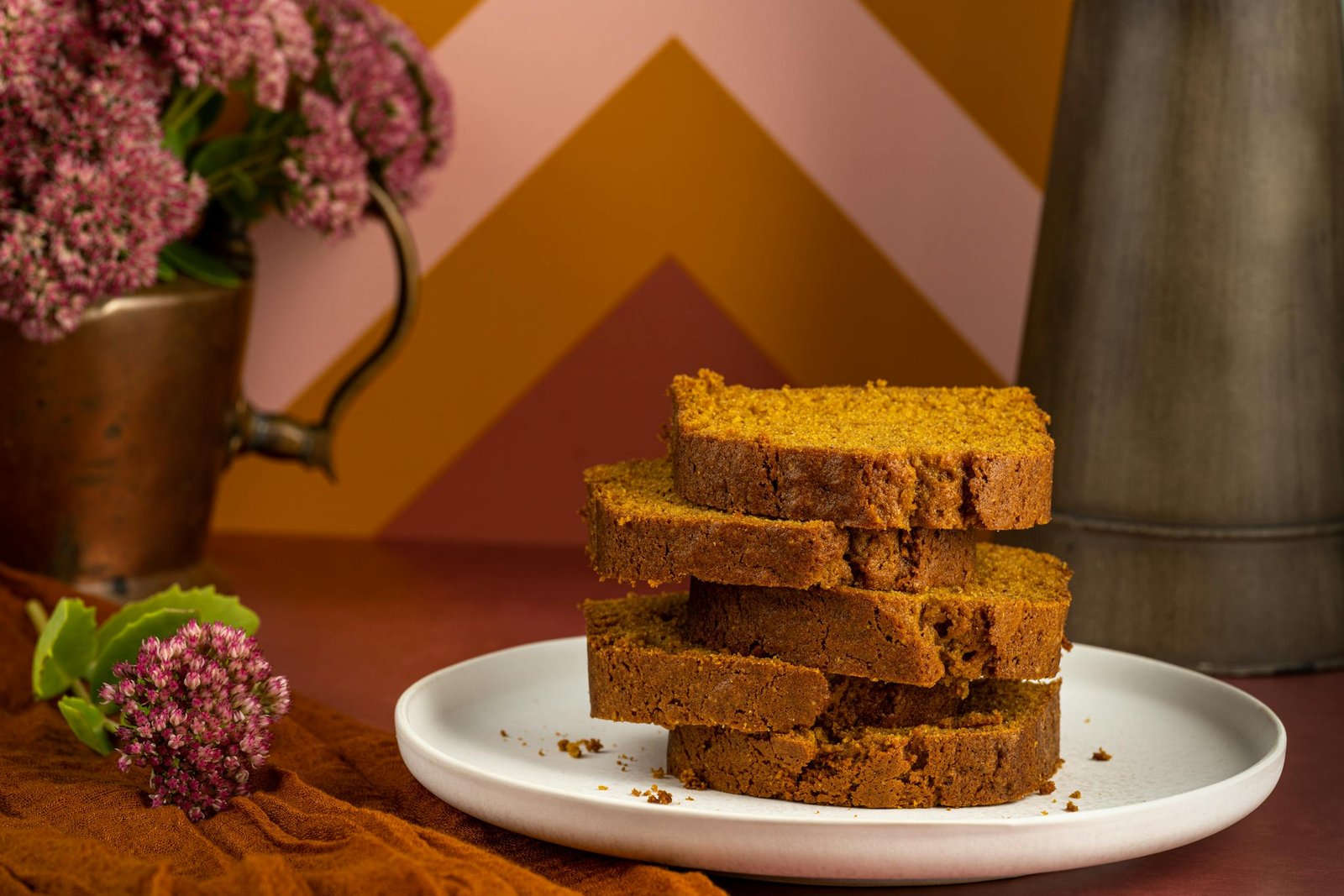 Stack of delicious pumpkin bread slices on a white plate with a cozy fall background.